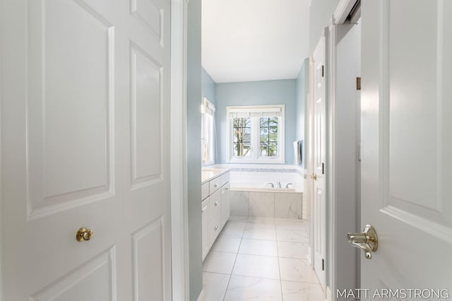 bathroom with a garden tub, marble finish floor, and vanity