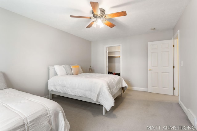 bedroom with light carpet, a walk in closet, a ceiling fan, baseboards, and a closet