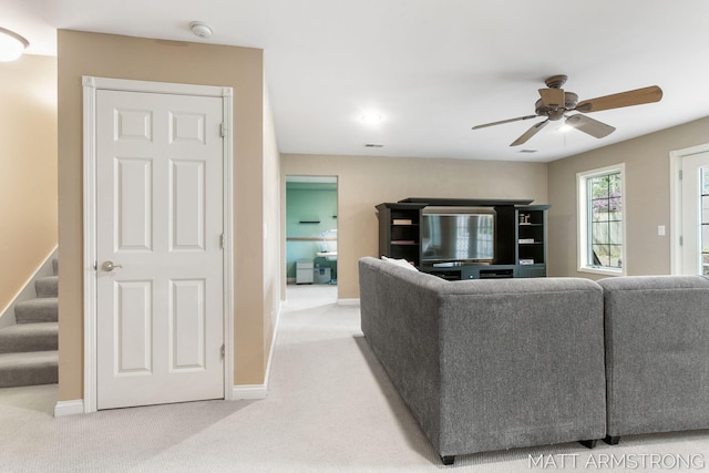 carpeted living area featuring stairway, baseboards, and a ceiling fan