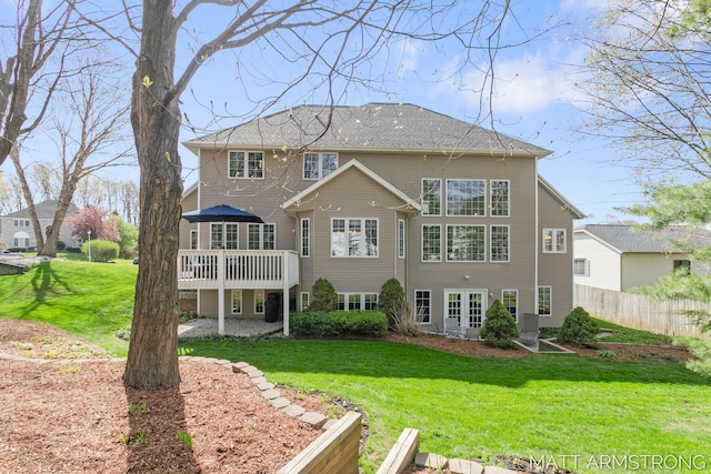 rear view of property featuring a lawn, a wooden deck, french doors, and fence