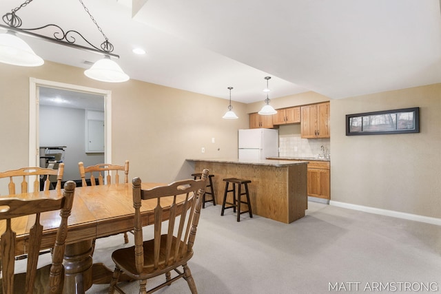 dining space featuring light colored carpet and baseboards