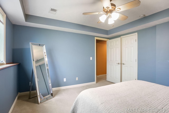 carpeted bedroom featuring baseboards, ceiling fan, a raised ceiling, and visible vents