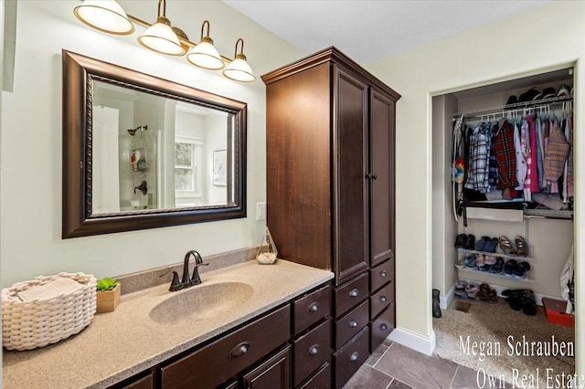 full bathroom featuring a spacious closet, tile patterned flooring, and vanity