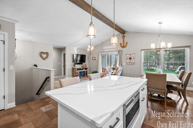 kitchen featuring stainless steel microwave, light stone counters, lofted ceiling with beams, a notable chandelier, and hanging light fixtures
