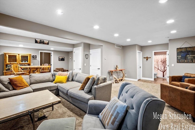 living area featuring visible vents, recessed lighting, baseboards, and light carpet