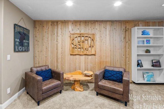 sitting room with recessed lighting, wood walls, carpet, and baseboards
