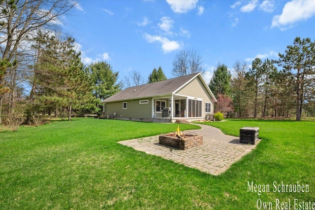 back of house with a lawn, a sunroom, a patio area, and an outdoor fire pit