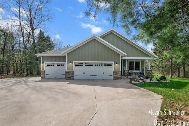 craftsman-style house featuring an attached garage, a front lawn, stone siding, and concrete driveway
