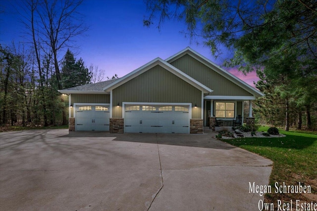 craftsman inspired home with an attached garage, a front yard, stone siding, and concrete driveway