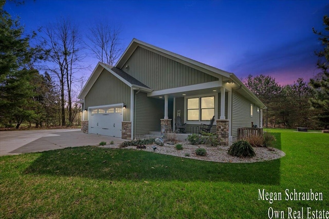 craftsman house featuring covered porch, driveway, a lawn, an attached garage, and stone siding
