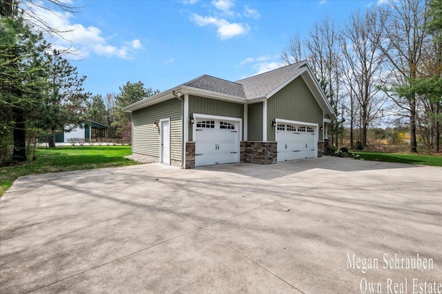 view of side of property featuring a yard, an attached garage, concrete driveway, and stone siding