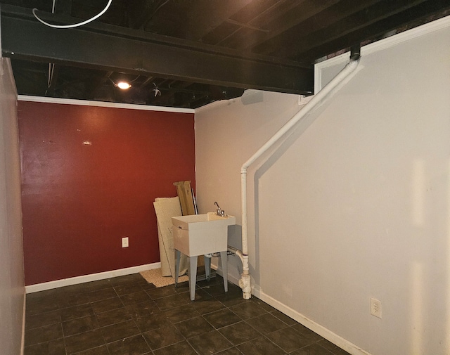 below grade area with baseboards, a sink, and dark tile patterned flooring