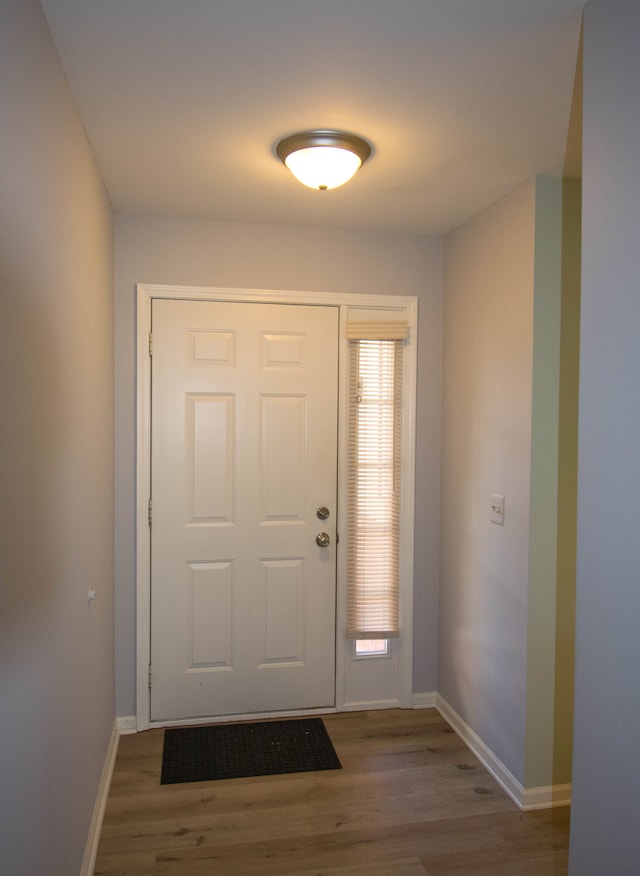 doorway to outside featuring baseboards and wood finished floors