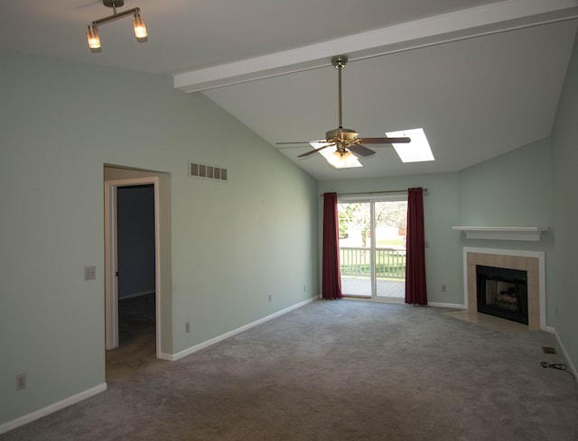 unfurnished living room featuring carpet flooring, a fireplace, a ceiling fan, visible vents, and lofted ceiling with skylight