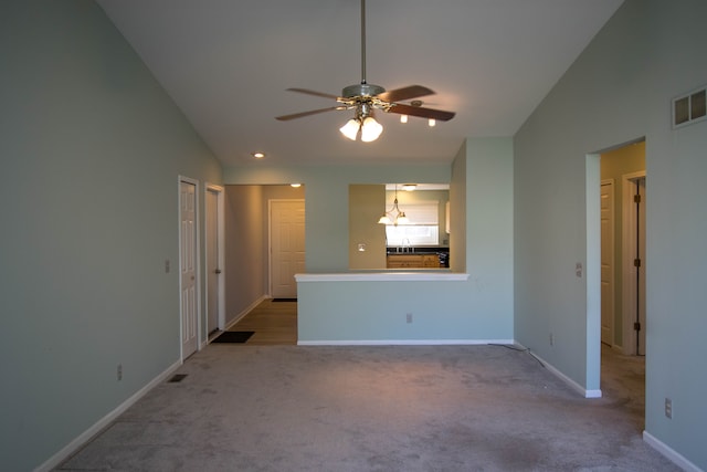 unfurnished living room featuring visible vents, baseboards, ceiling fan with notable chandelier, lofted ceiling, and light carpet