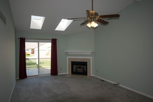 unfurnished living room featuring carpet, a ceiling fan, baseboards, a tile fireplace, and lofted ceiling with skylight