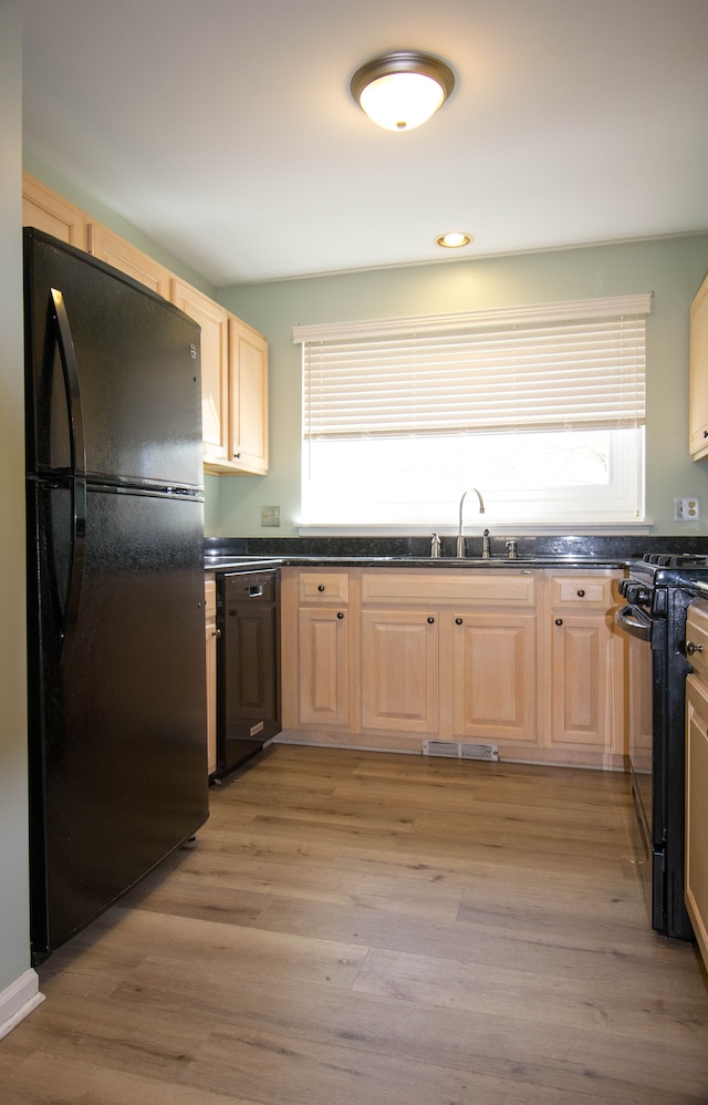 kitchen with dark countertops, light brown cabinets, black appliances, and visible vents