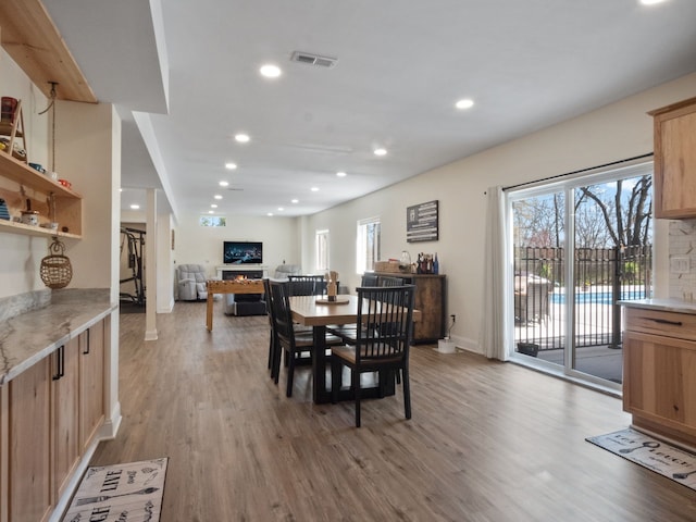 7136 N Meadows Trl, Dexter, MI 48130 - dining area with recessed lighting, light wood finished floors, a warm lit fireplace, and visible vents