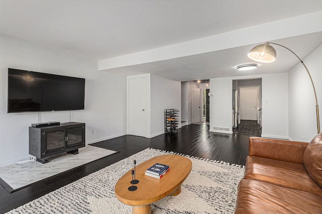 living area featuring baseboards, visible vents, wood finished floors, and a wood stove