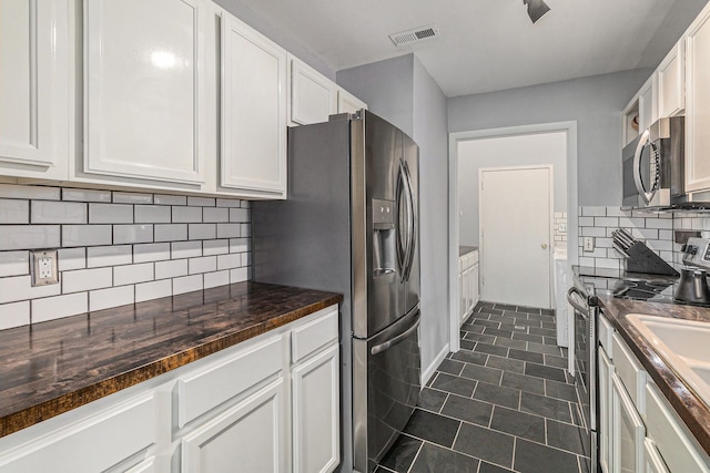 kitchen featuring white cabinets, dark tile patterned flooring, appliances with stainless steel finishes, and visible vents