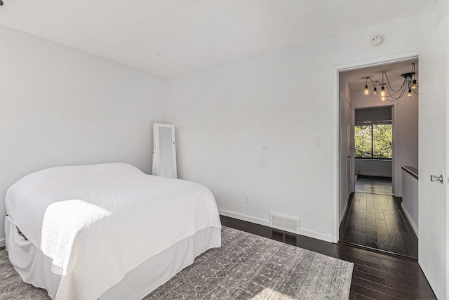 bedroom featuring baseboards, a notable chandelier, dark wood finished floors, and visible vents