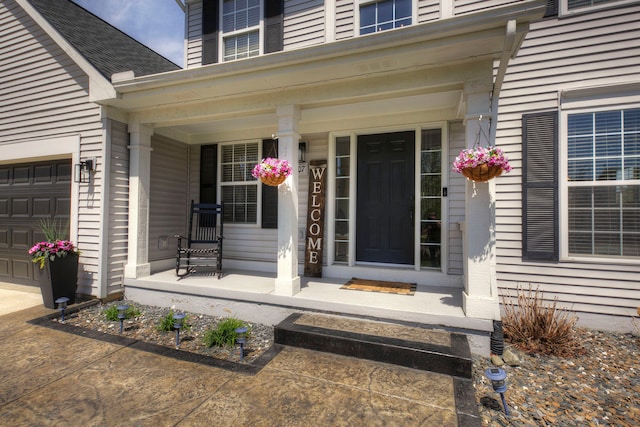 doorway to property featuring covered porch, an attached garage, and roof with shingles