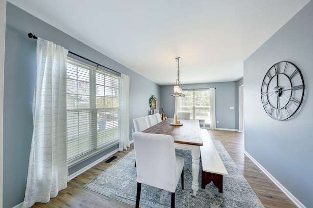 dining space with baseboards, visible vents, wood finished floors, and a chandelier