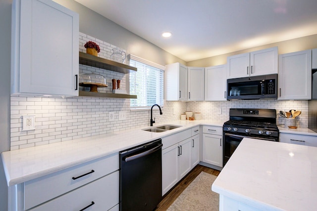 kitchen with stainless steel gas stove, black dishwasher, a sink, dark wood finished floors, and backsplash