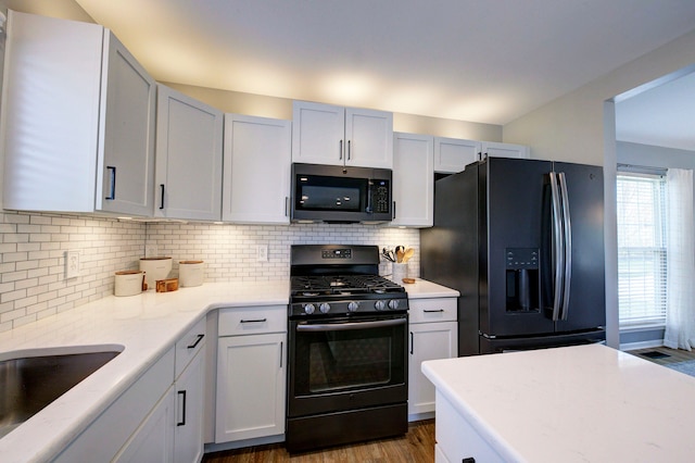 kitchen featuring backsplash, dark wood-style flooring, light stone counters, and black appliances