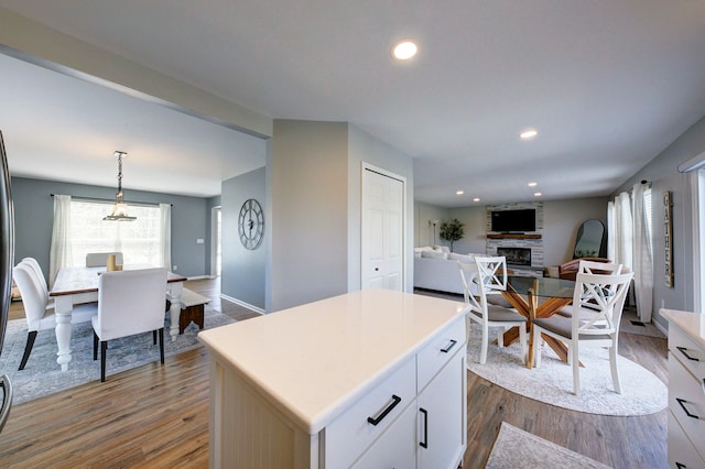 kitchen with a stone fireplace, light countertops, dark wood finished floors, and a kitchen island