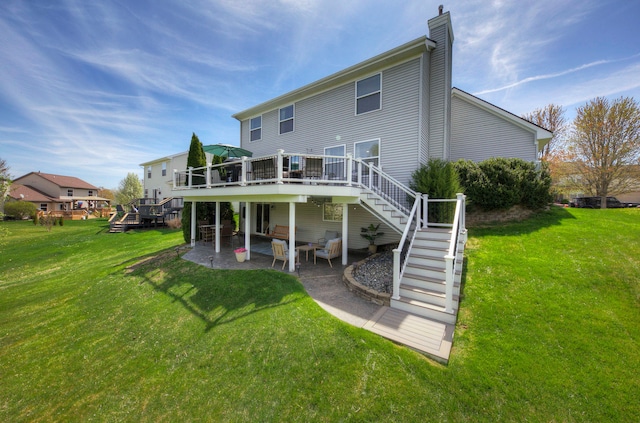 rear view of property featuring stairs, a deck, a chimney, a patio area, and a lawn