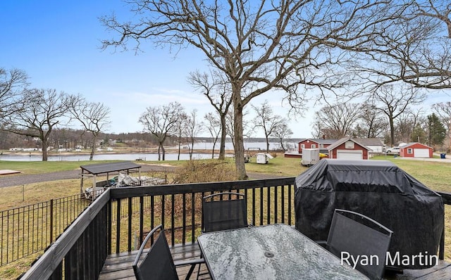 deck featuring a lawn, outdoor dining area, a water view, and a grill