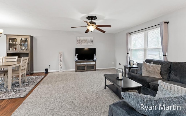 living room featuring baseboards, a ceiling fan, and dark wood-style floors