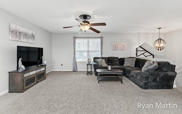 carpeted living area featuring baseboards and ceiling fan with notable chandelier