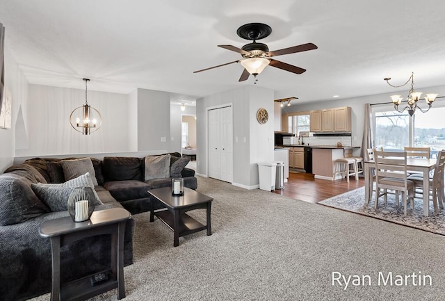 living room with baseboards, carpet, and ceiling fan with notable chandelier