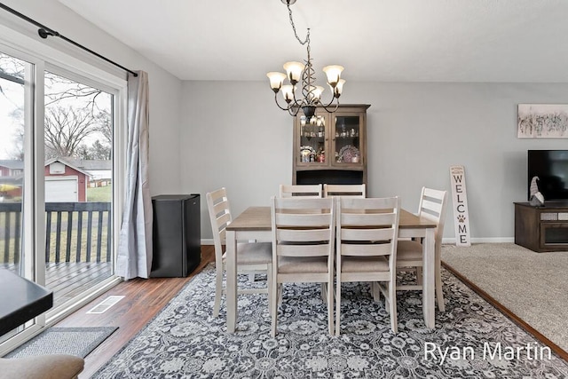 dining area with baseboards, an inviting chandelier, wood finished floors, and visible vents