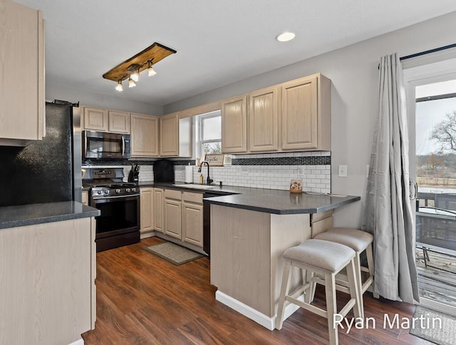 kitchen featuring light brown cabinetry, a sink, freestanding refrigerator, stainless steel microwave, and range with gas cooktop