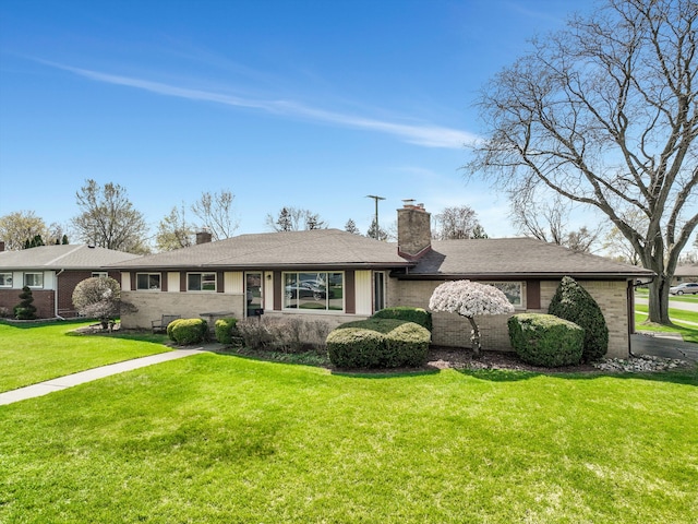 ranch-style house with brick siding, a front yard, and a chimney