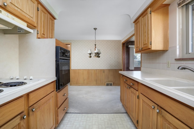kitchen with light countertops, visible vents, under cabinet range hood, and oven