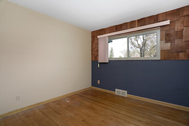 spare room with visible vents, baseboards, and wood finished floors