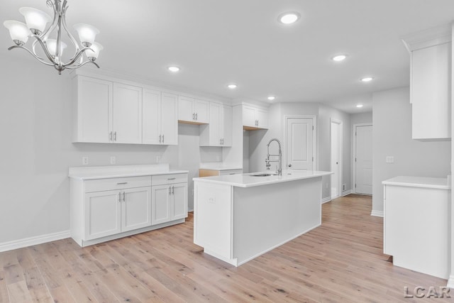kitchen featuring white cabinetry, baseboards, a sink, and light wood-style flooring