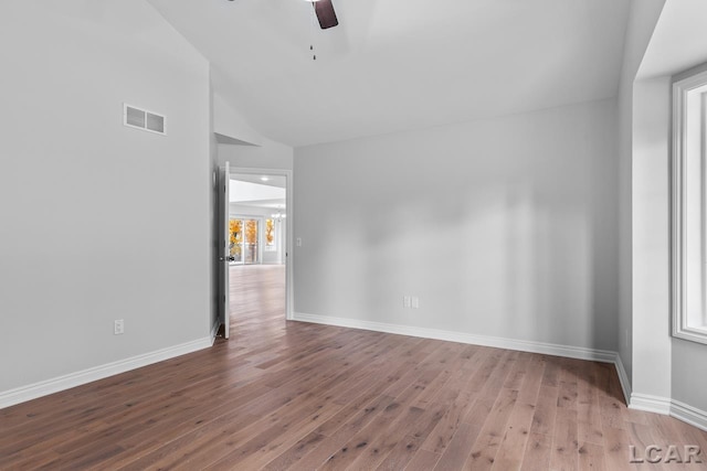 empty room with visible vents, lofted ceiling, wood finished floors, baseboards, and a ceiling fan