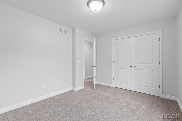 unfurnished bedroom with visible vents, carpet flooring, baseboards, and a closet