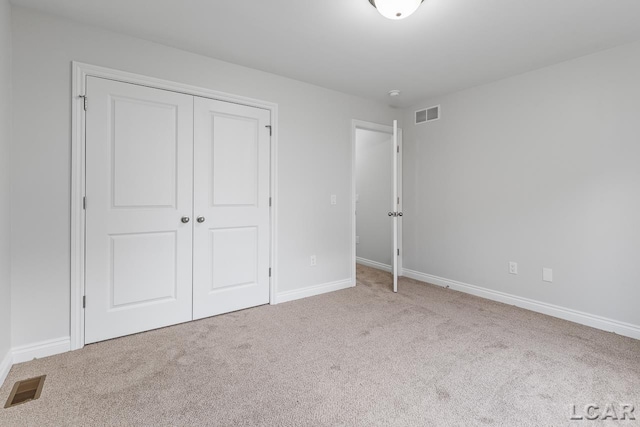 unfurnished bedroom featuring visible vents, carpet, baseboards, and a closet