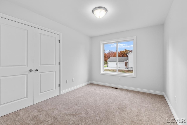unfurnished bedroom with carpet floors, baseboards, a closet, and visible vents