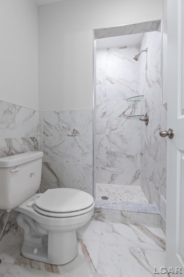 full bath with a marble finish shower, toilet, tile walls, and marble finish floor