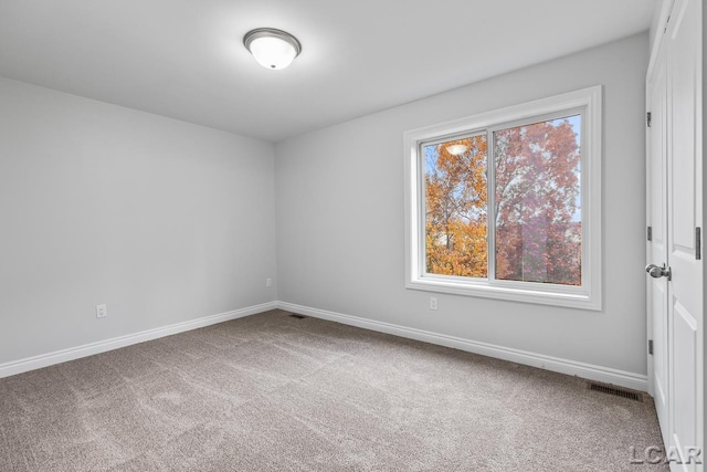 carpeted empty room featuring baseboards and visible vents