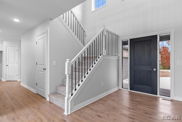foyer entrance with recessed lighting, baseboards, stairs, and wood finished floors