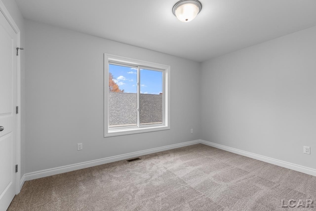 empty room featuring baseboards, visible vents, and carpet