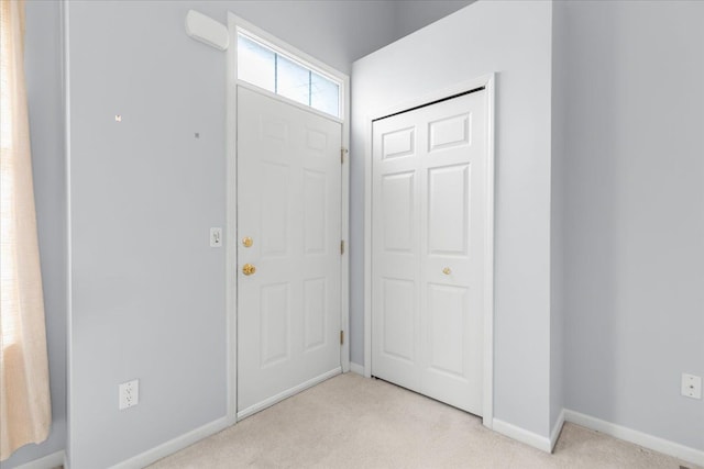 entrance foyer featuring baseboards and light carpet
